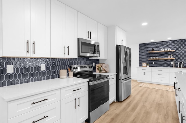 kitchen featuring white cabinets, appliances with stainless steel finishes, backsplash, and light hardwood / wood-style flooring