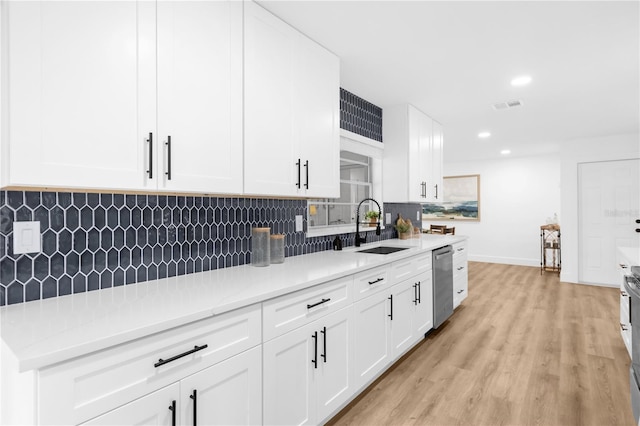 kitchen with white cabinetry, sink, stainless steel appliances, decorative backsplash, and light wood-type flooring