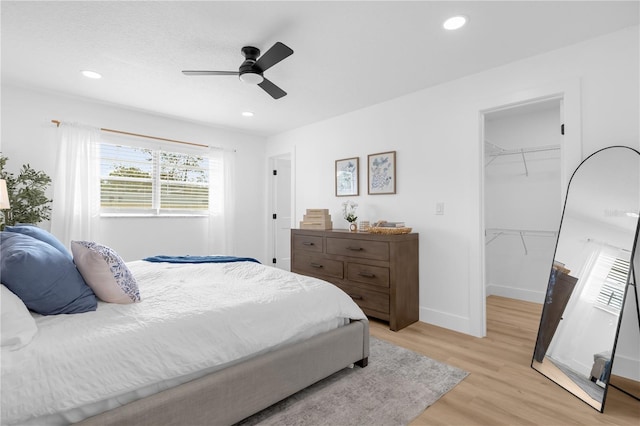 bedroom with ceiling fan, light hardwood / wood-style floors, a spacious closet, and a closet