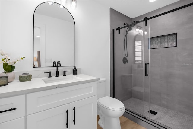 bathroom with hardwood / wood-style floors, vanity, toilet, and walk in shower