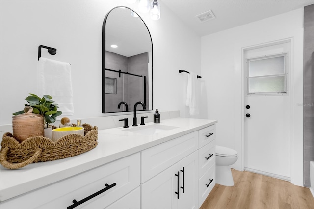 bathroom featuring walk in shower, vanity, wood-type flooring, and toilet