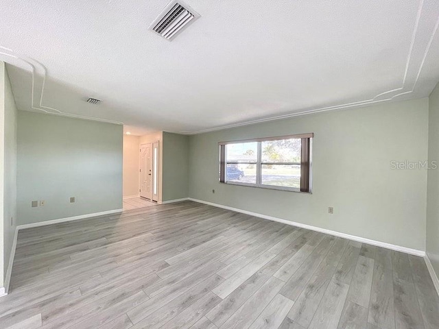 spare room featuring light hardwood / wood-style flooring and a textured ceiling