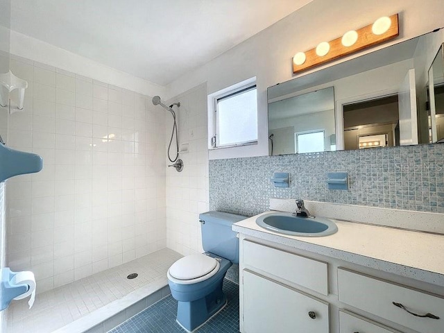 bathroom featuring decorative backsplash, a tile shower, vanity, tile patterned flooring, and toilet