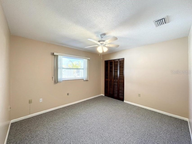 unfurnished room featuring ceiling fan, carpet floors, and a textured ceiling