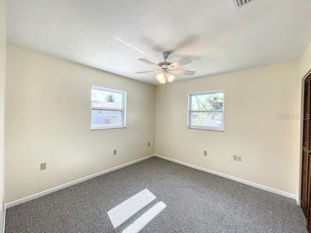 carpeted empty room featuring a textured ceiling, plenty of natural light, and ceiling fan