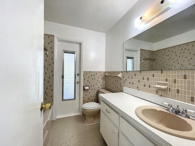 bathroom with tile patterned flooring, a shower, toilet, vanity, and tile walls