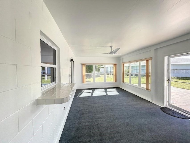 unfurnished sunroom featuring ceiling fan