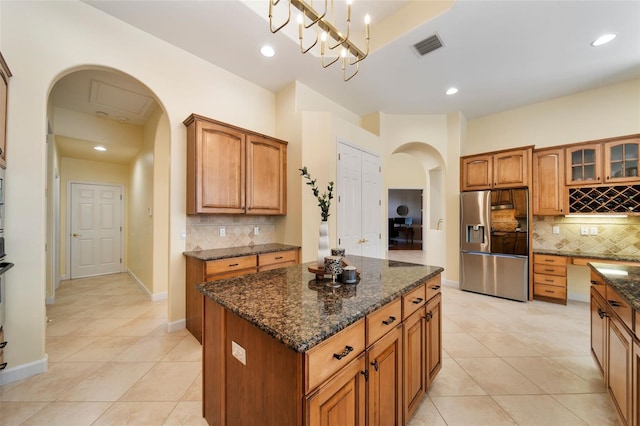 kitchen with stainless steel fridge, backsplash, decorative light fixtures, and a kitchen island