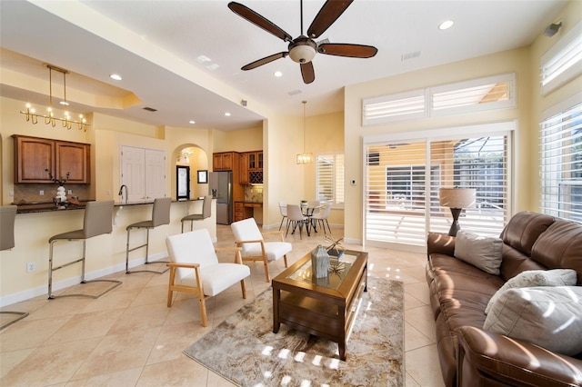 tiled living room with ceiling fan with notable chandelier