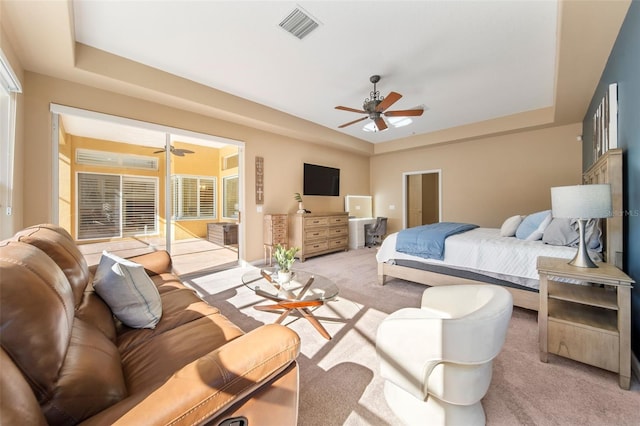 bedroom with ceiling fan, light colored carpet, and a tray ceiling