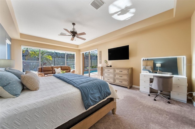 carpeted bedroom with a tray ceiling, access to exterior, and ceiling fan