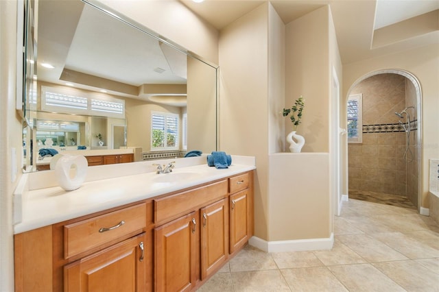 bathroom with tile patterned flooring, vanity, a raised ceiling, and tiled shower