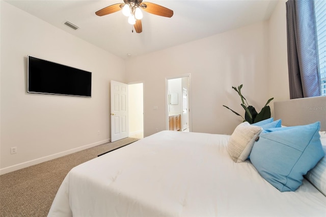 carpeted bedroom with ensuite bath and ceiling fan