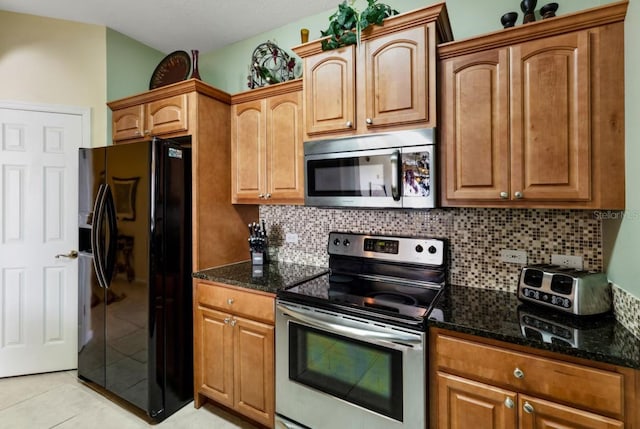 kitchen with decorative backsplash, light tile patterned flooring, dark stone countertops, and stainless steel appliances