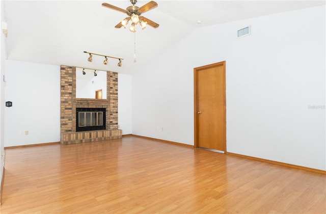 unfurnished living room featuring vaulted ceiling, light hardwood / wood-style flooring, a brick fireplace, and ceiling fan