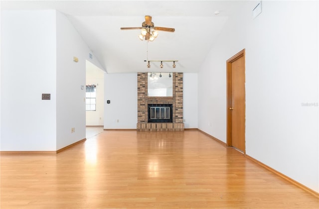 unfurnished living room with a brick fireplace, ceiling fan, vaulted ceiling, and light hardwood / wood-style flooring