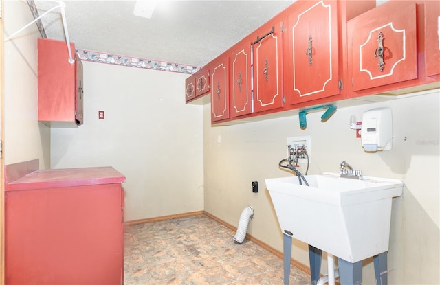 clothes washing area featuring washer hookup, cabinets, sink, and a textured ceiling