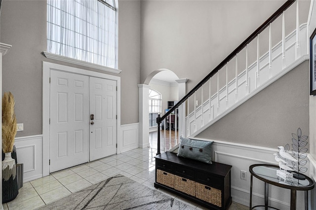 tiled entrance foyer with decorative columns and a towering ceiling