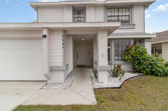 view of exterior entry with a garage and a yard