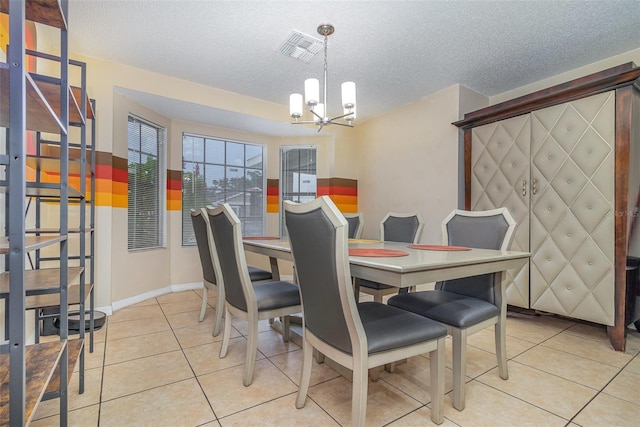 tiled dining space with a textured ceiling and a chandelier