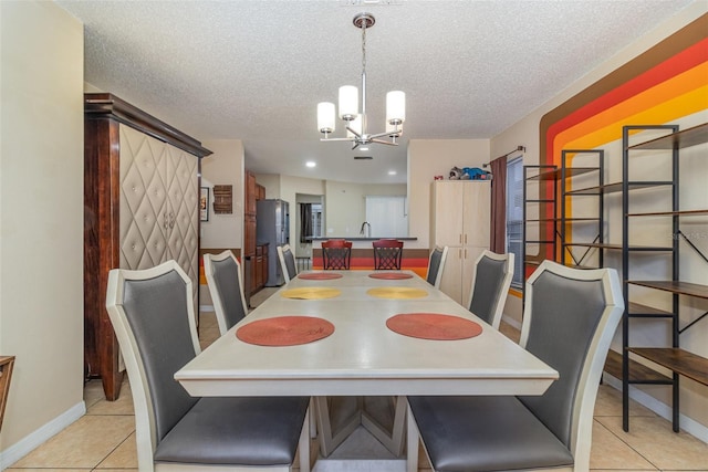 tiled dining area featuring a textured ceiling, sink, and a chandelier