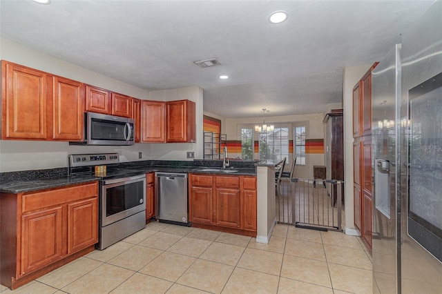 kitchen with a chandelier, stainless steel appliances, hanging light fixtures, kitchen peninsula, and sink