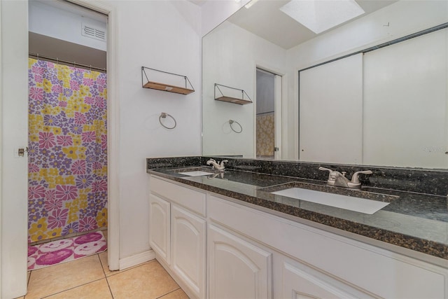 bathroom with a shower with shower curtain, vanity, tile patterned flooring, and a skylight