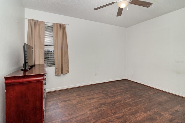 spare room featuring dark wood-type flooring, a textured ceiling, and ceiling fan