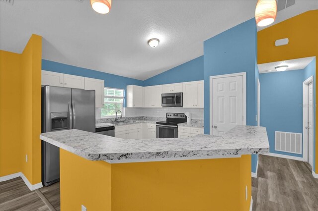 kitchen with sink, stainless steel appliances, a kitchen island, vaulted ceiling, and white cabinets