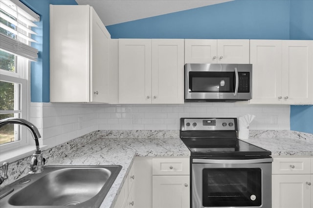 kitchen featuring white cabinets, sink, stainless steel appliances, and vaulted ceiling