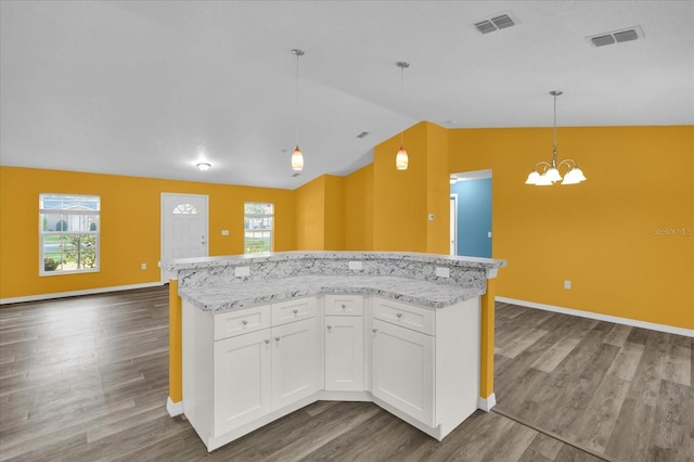 kitchen featuring pendant lighting, dark wood-type flooring, white cabinets, vaulted ceiling, and a notable chandelier