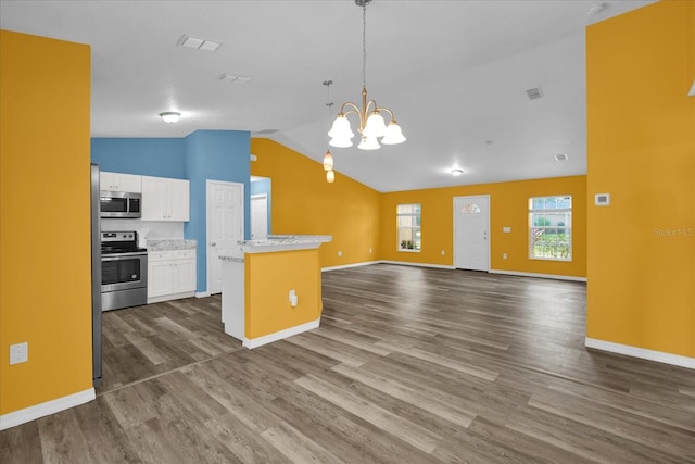 kitchen with stainless steel appliances, vaulted ceiling, dark wood-type flooring, white cabinets, and hanging light fixtures