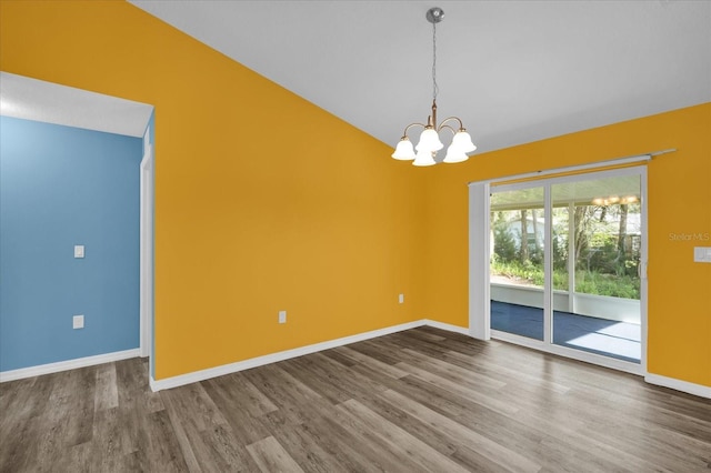 unfurnished room featuring hardwood / wood-style floors, lofted ceiling, and an inviting chandelier