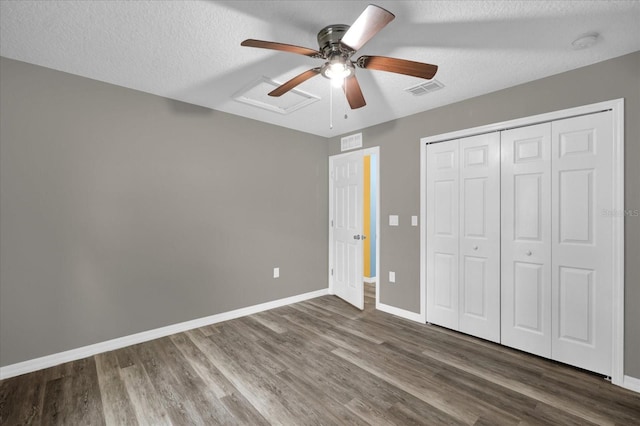 unfurnished bedroom with ceiling fan, dark hardwood / wood-style flooring, a textured ceiling, and a closet