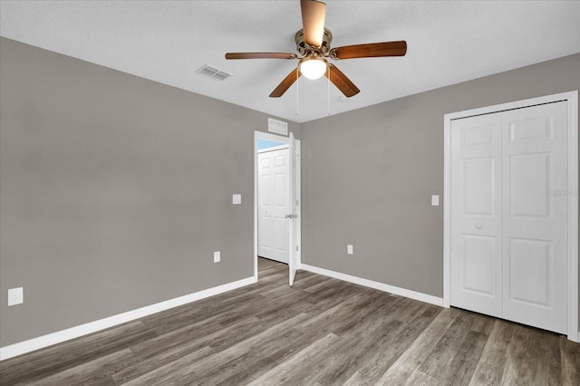 unfurnished bedroom with a closet, hardwood / wood-style flooring, and ceiling fan