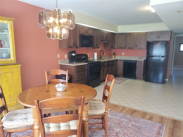 kitchen with sink, hanging light fixtures, light hardwood / wood-style flooring, dark brown cabinets, and black appliances