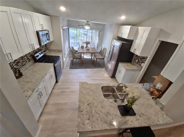 kitchen featuring white cabinets, backsplash, light stone countertops, and stainless steel appliances