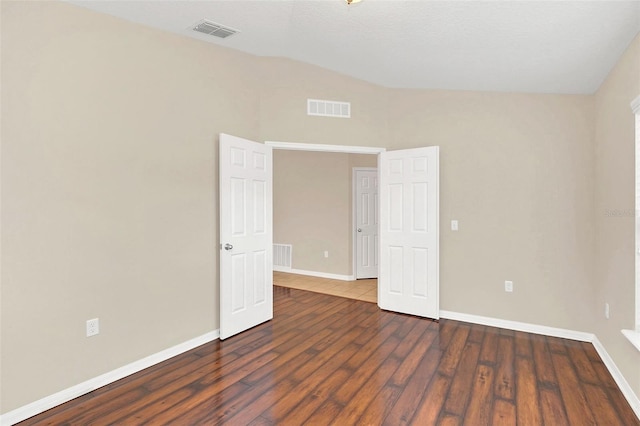 spare room with dark hardwood / wood-style floors and vaulted ceiling