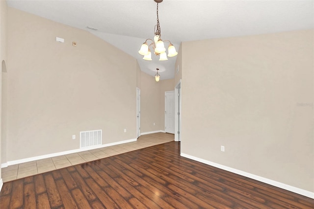 spare room featuring hardwood / wood-style flooring, lofted ceiling, and an inviting chandelier