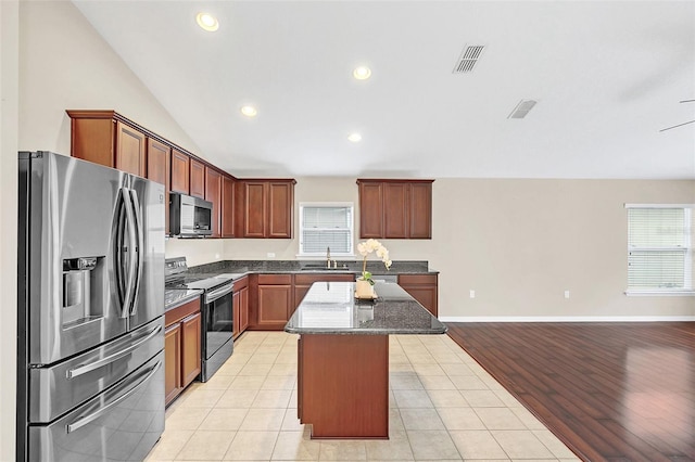 kitchen featuring light tile patterned floors, a center island, stainless steel appliances, and sink