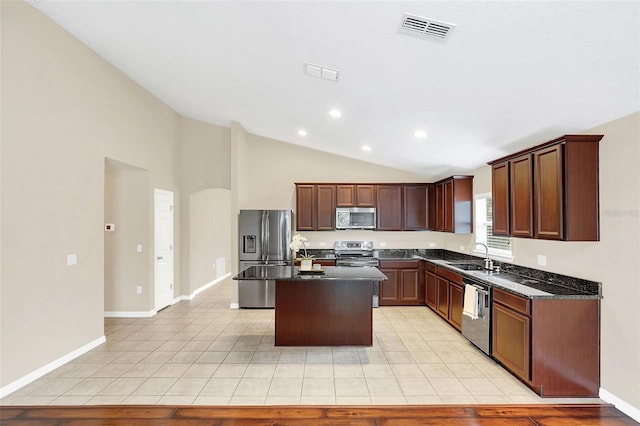 kitchen with a center island, sink, stainless steel appliances, dark stone counters, and light tile patterned floors