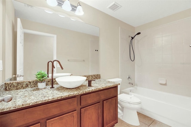 full bathroom with tile patterned flooring, vanity, tiled shower / bath combo, and toilet