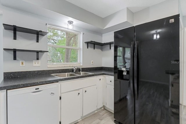 kitchen with light wood-type flooring, black refrigerator with ice dispenser, white dishwasher, sink, and white cabinets