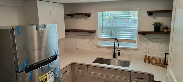 kitchen with sink, gray cabinets, tasteful backsplash, and stainless steel refrigerator