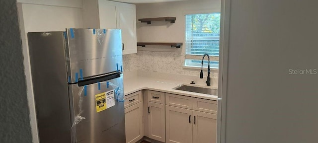 kitchen featuring sink, white cabinets, a healthy amount of sunlight, and stainless steel refrigerator