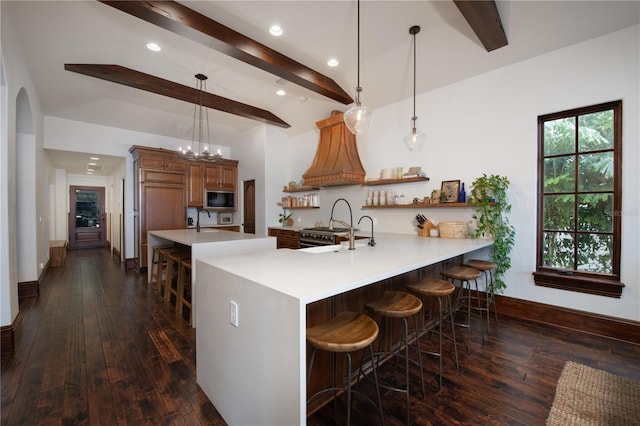 kitchen with black microwave, dark wood-type flooring, a kitchen breakfast bar, beamed ceiling, and decorative light fixtures