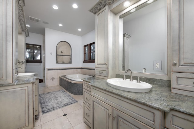 bathroom featuring tile patterned flooring, vanity, and a relaxing tiled tub