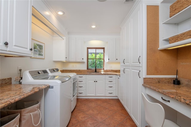 clothes washing area featuring washing machine and clothes dryer, sink, cabinets, crown molding, and light tile patterned floors