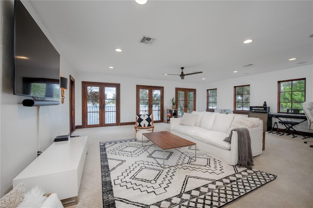 living room featuring a wealth of natural light, light carpet, french doors, and ceiling fan