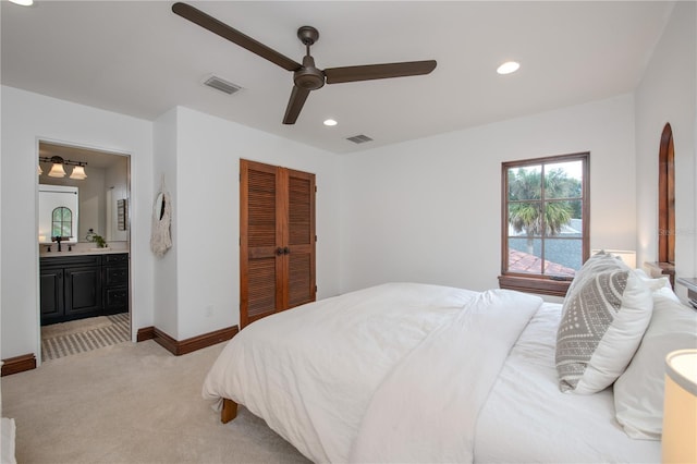 carpeted bedroom featuring ceiling fan, ensuite bathroom, and a closet